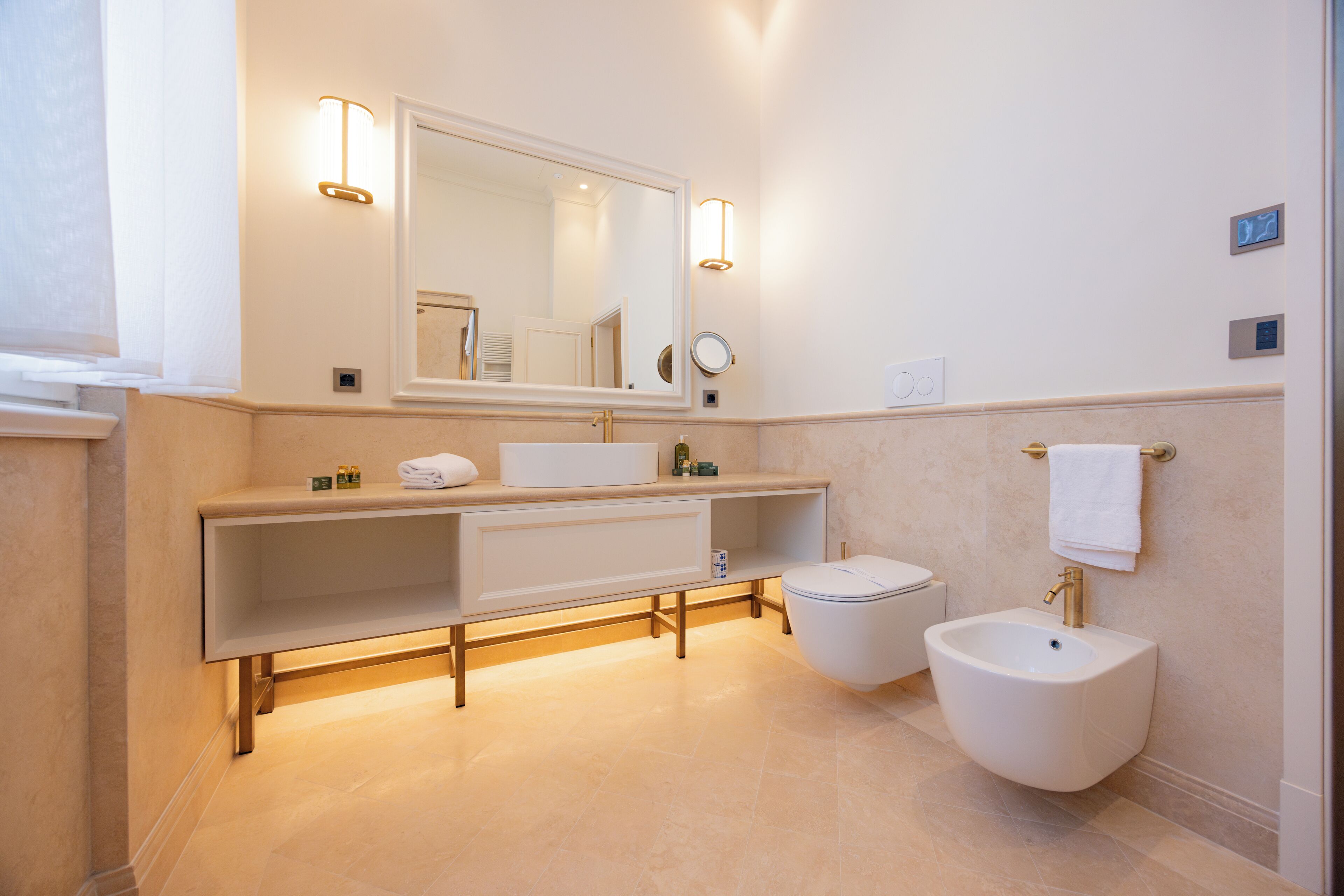 Un baño moderno con un espejo grande, un tocador con lavamanos, un bidé y un perchero para toallas.