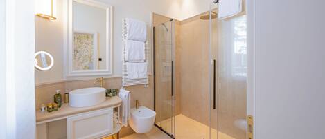 A modern bathroom with a round sink, a glass-enclosed shower, and a toilet.