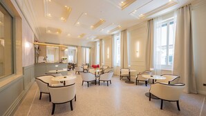 A spacious hotel lobby with multiple seating areas, a reception desk, and large windows allowing natural light.