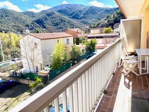 A balcony with a view of a mountainous landscape, a small table, and chairs. - Cozy F2 Apartment with Balcony, Fully Equipped Kitchen, Pet-Friendly in Amélie-les-Bains (Amélie-les-Bains-Palalda)