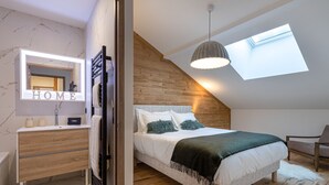 Une chambre avec un puits de lumière, un lit avec des oreillers, une table de chevet et un miroir.