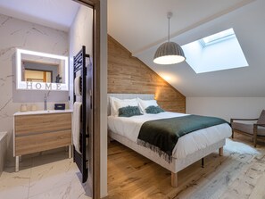 A bedroom with a skylight, a bed with a green throw, a wooden dresser, and a mirror with 'HOME' on it.