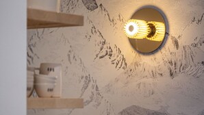 Un mur orné d’un motif de montagnes et un luminaire circulaire.
