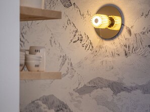 A wall with a mountain mural and a circular light fixture.