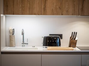 A modern kitchen with a wooden cabinet, a stainless steel toaster, a knife block, and a knife holder.