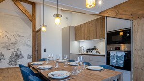 Une cuisine moderne équipée d’un four et d’un micro-ondes Bosch, de meubles en bois et d’un coin repas avec une table en bois et des chaises bleues.