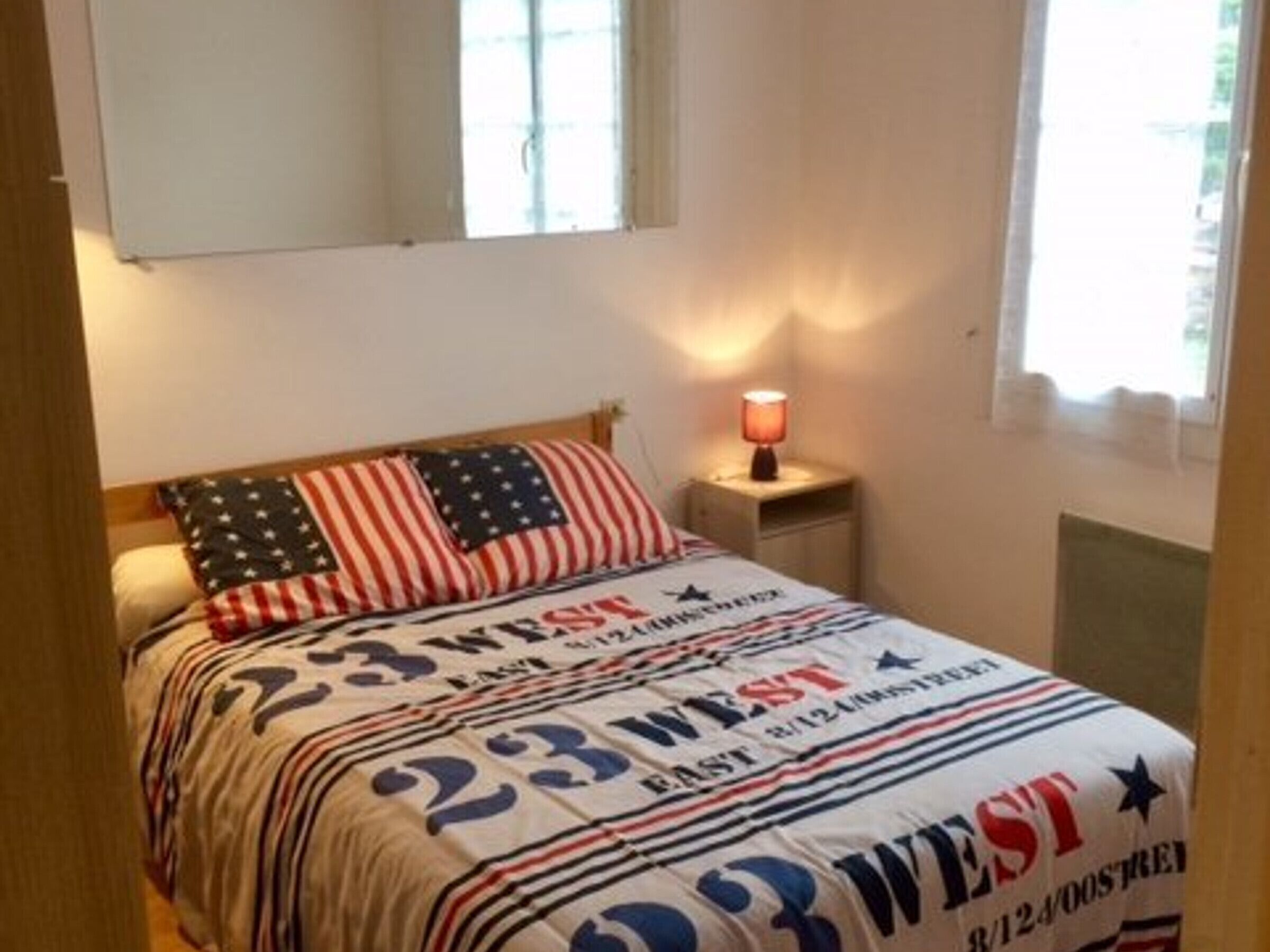 Een slaapkamer met een bed, nachtkastje, lamp en raam.