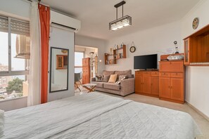 Une chambre à coucher avec un lit, un canapé, une télévision et des meubles en bois.
