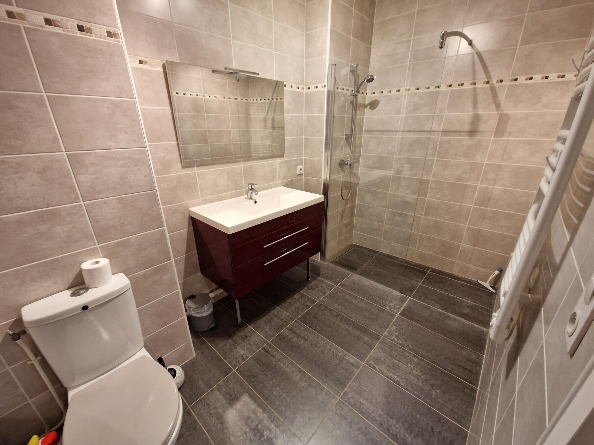 A bathroom with a toilet, sink, vanity, and shower area.