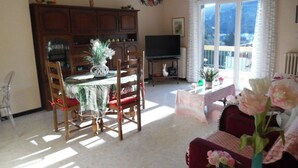 Una sala de estar con comedor, televisor y vistas al exterior.