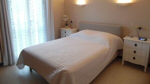 Una habitación de hotel con una cama grande, una mesita de noche y una ventana con cortinas.