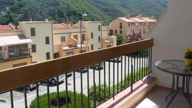 Un balcón con vistas a una zona residencial y montañas.