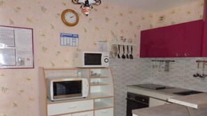 A compact kitchen with a microwave, stove, and cabinets. - Cozy Studio for 2 with Balcony, Wi-Fi near Thermes, Amélie-les-Bains (Amélie-les-Bains-Palalda)