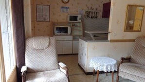 A compact living space with a kitchenette, a dining area with a table and chairs, and a sofa. - Cozy Studio for 2 with Balcony, Wi-Fi near Thermes, Amélie-les-Bains (Amélie-les-Bains-Palalda)