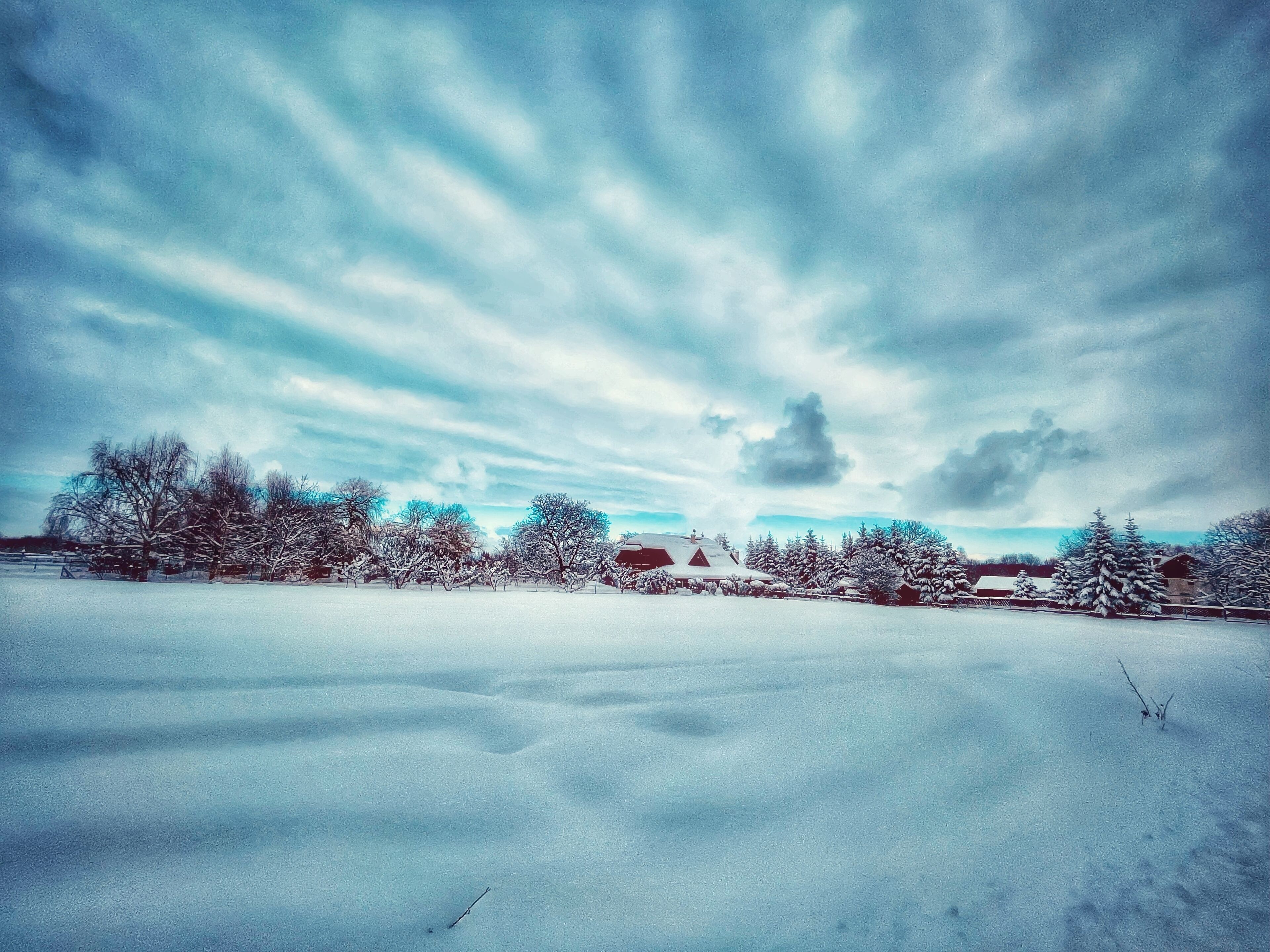 A snowy landscape with a clear sky and a few buildings in the distance.