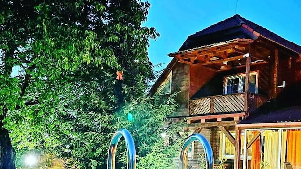 Una casa de madera con piscina, rodeada de árboles.