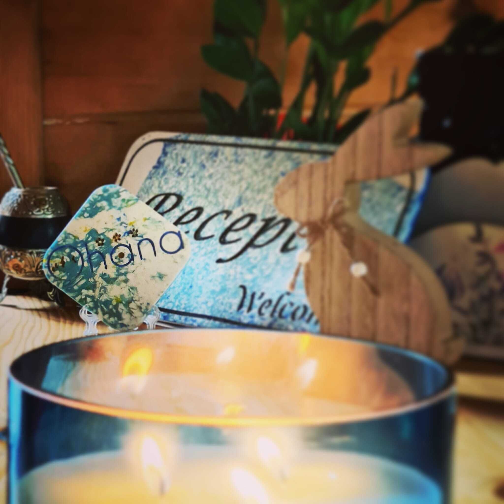 Una vela en un recipiente azul con un letrero de madera que dice 