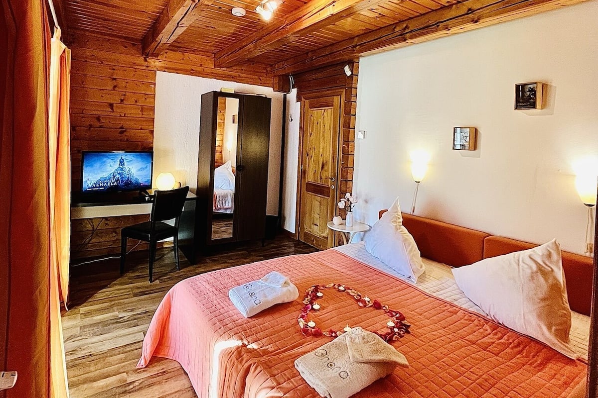 Una habitación con paneles de madera, una cama, un escritorio y un televisor.