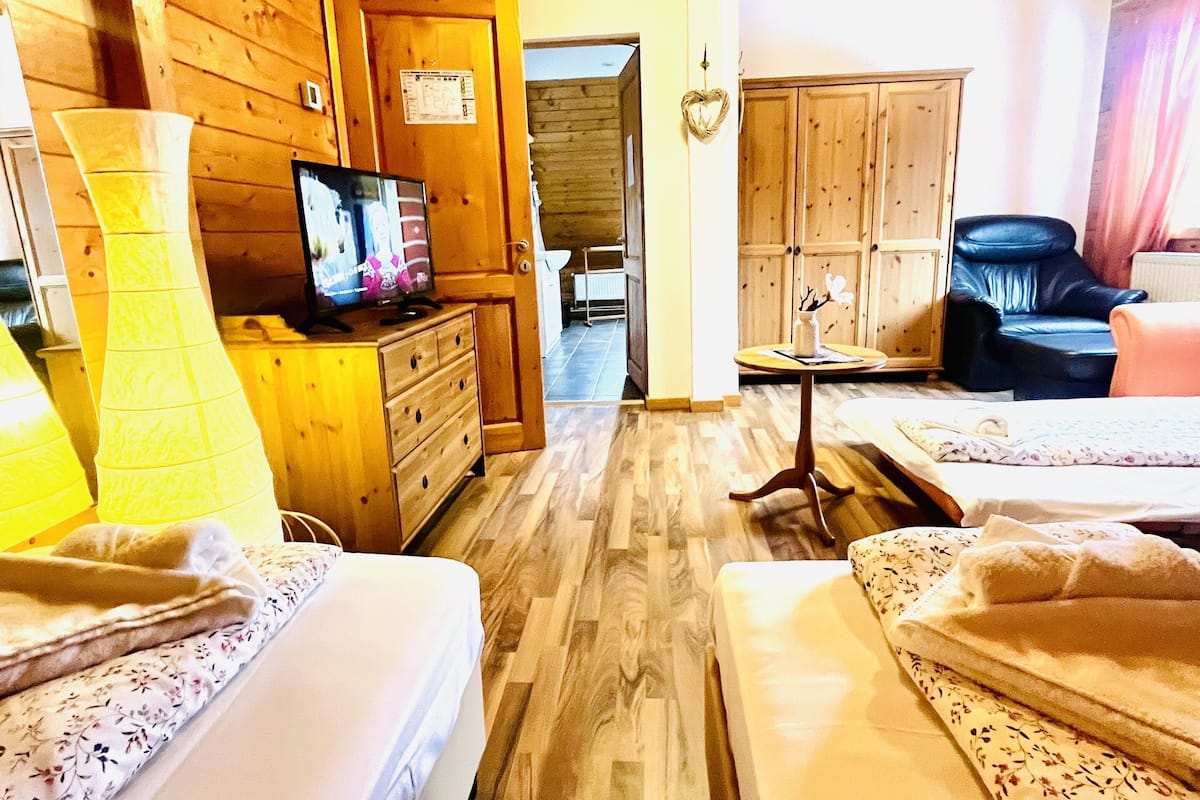 Interior de una cabaña de madera con dos camas, un televisor y un armario de madera.