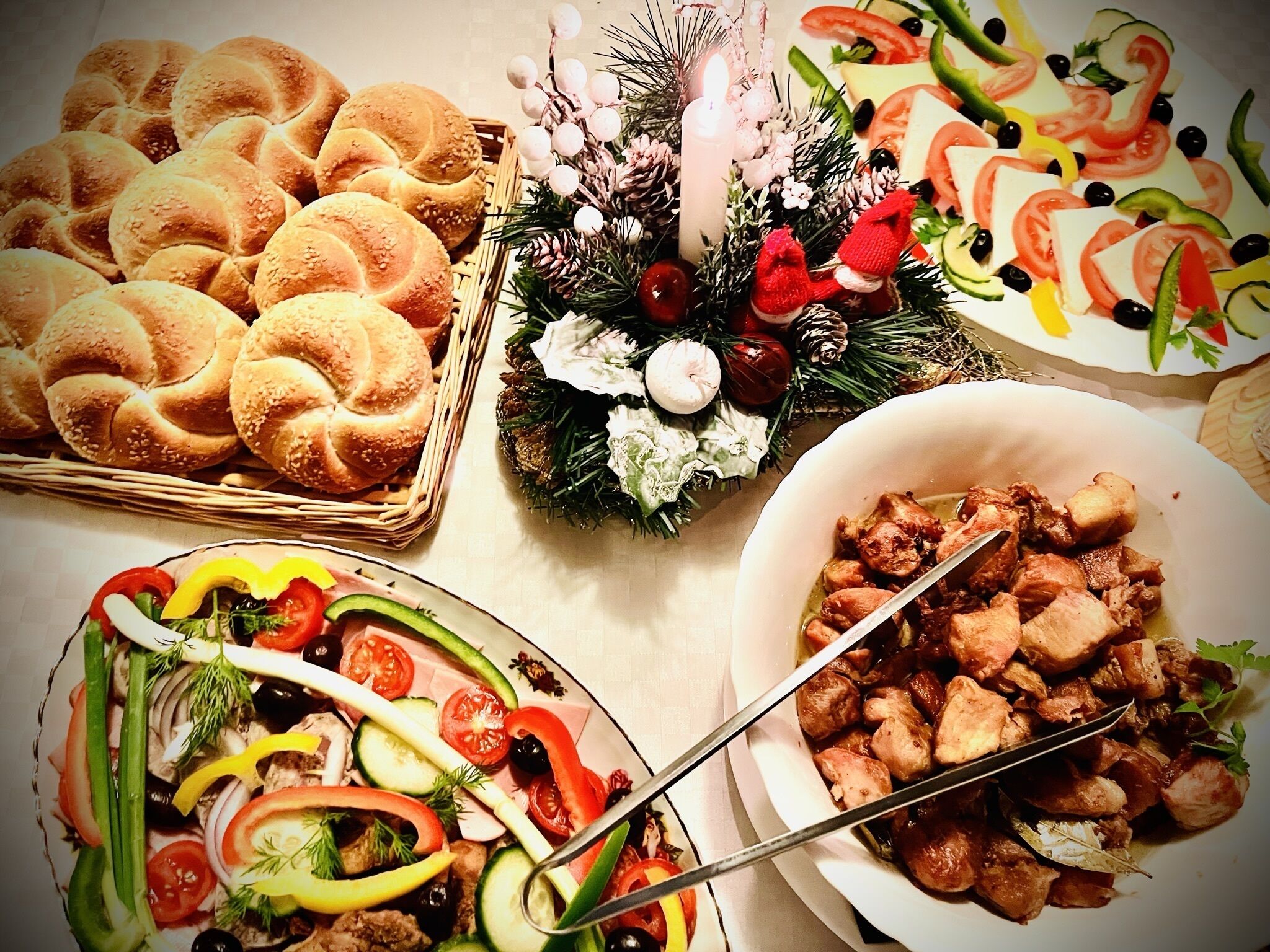 Een tafel met diverse etenswaren, waaronder brood, een salade en een schaal vlees.
