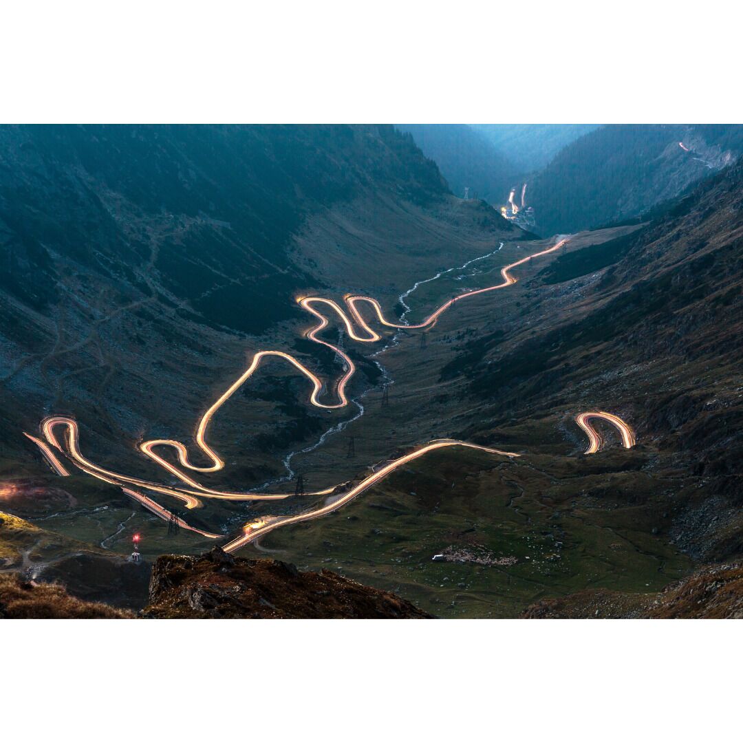 A winding mountain road with a bridge and a valley.