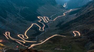 A winding mountain road with a bridge and a valley.