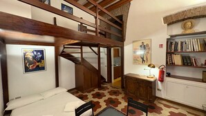 Ein Zimmer mit Etagenbett, Schreibtisch mit Lampe, Bücherregal und einer Treppe.