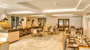 A modern hotel lobby with a central bar area, dining tables, and a reception desk. - Iris Lite Corbett (Ramnagar)