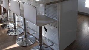 A modern kitchen with a central island, bar stools, and a large window with curtains. - MARKAIDA HOUSE WITH POOL (Mungia)