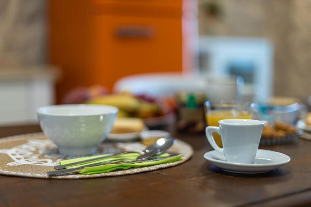 A breakfast setting with a white cup and saucer, a bowl, and a spoon on a placemat.