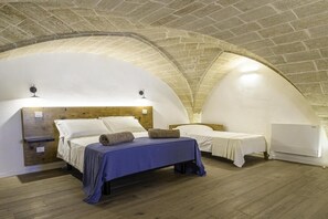 A cozy, arched room with two beds, wooden headboards, and a white air conditioning unit. - DIMORA LE SITE (Racale)
