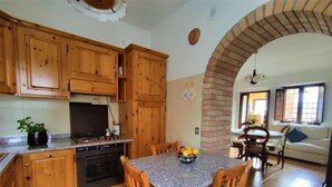 A kitchen with wooden cabinets, a stove, and a dining area with a table and chairs.