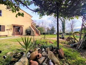 A rustic house with a garden featuring a stone pathway, potted plants, and a small fountain. - La Pergola by Interhome (Roccastrada)