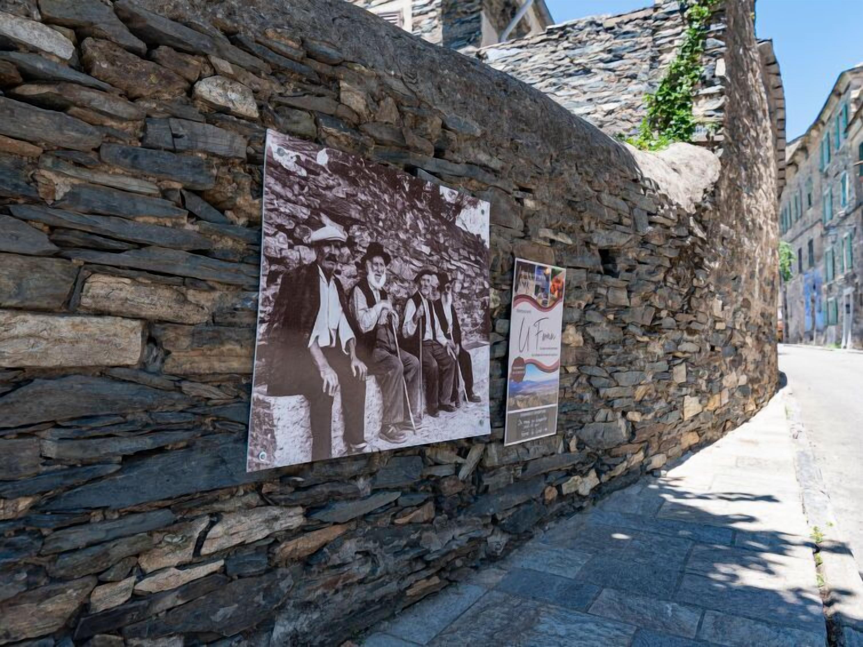 A stone wall with historical photographs and a poster.