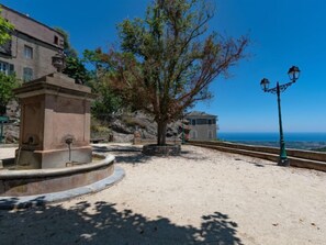 Enjoy serene ocean views and a tranquil atmosphere amidst a beautifully maintained outdoor space with a central fountain and a building with a pitched roof.