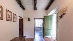 Un pasillo con un banco de madera, cuadros en la pared y una puerta verde que da a otra habitación.