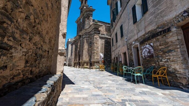 Una estrecha calle empedrada flanqueada por edificios históricos con una imponente estructura de torre.