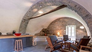 Una cocina acogedora con paredes de piedra, una barra, sillas de madera y un tazón rojo sobre la encimera.