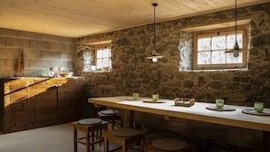 A rustic kitchen with stone walls, wooden beams, and a long counter with stools. - David am Buchhammerhof by Interhome (Kaunerberg)