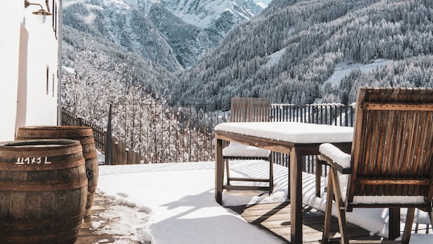 A wooden deck with a table and chairs, overlooking a snow-covered valley and mountains. - David am Buchhammerhof by Interhome (Kaunerberg)