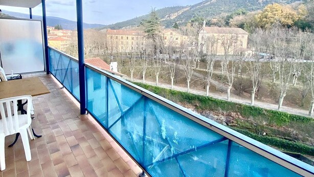 Un balcón con vistas a un viñedo y edificios al fondo.