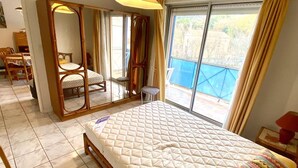 Un dormitorio con una cama grande, un armario, una silla y vistas al exterior.