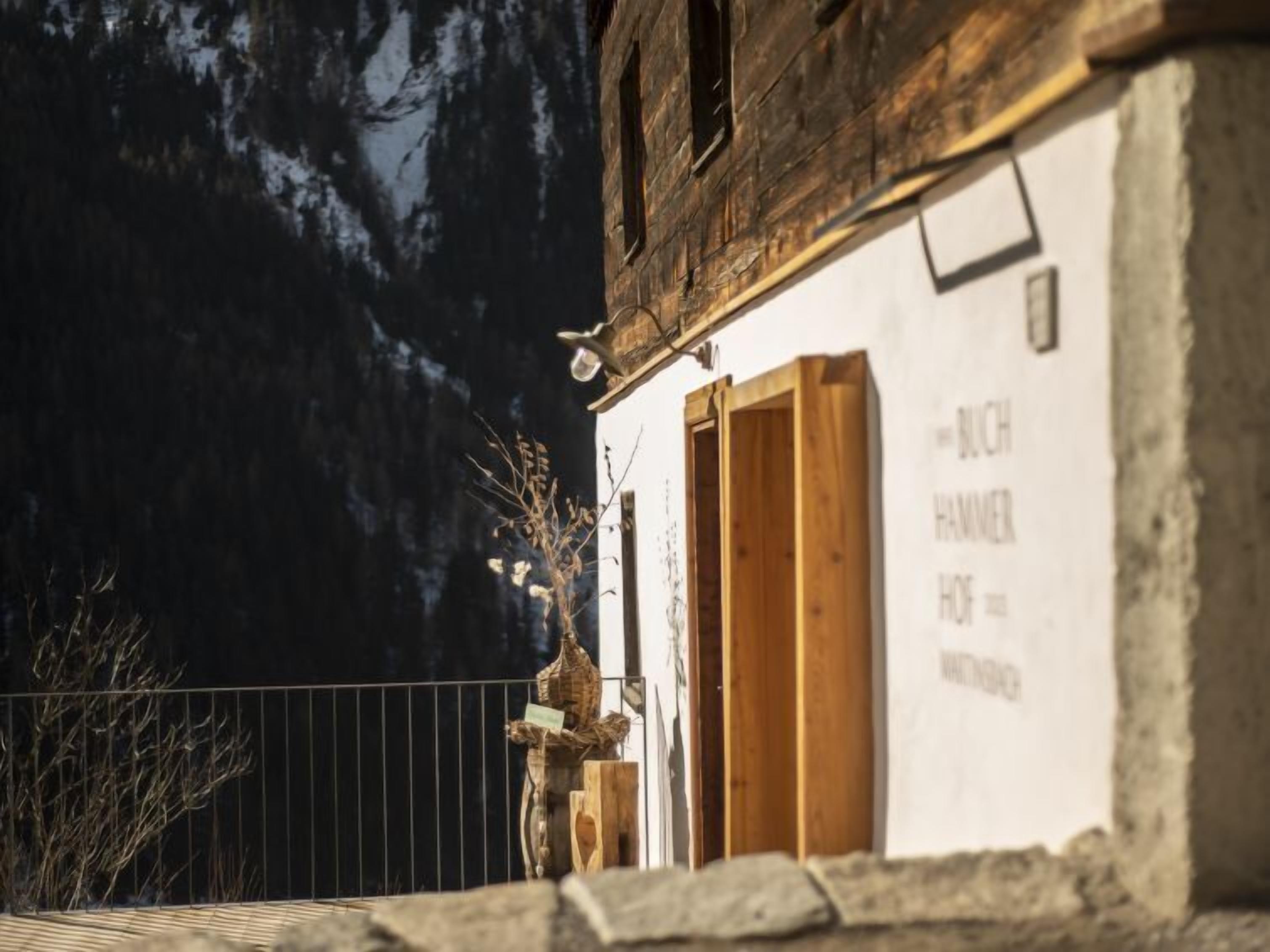 A rustic building with a wooden door and a sign that reads "BUCH HAMMER OF".