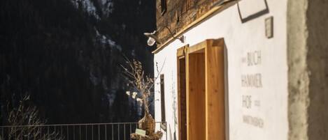A rustic building with a wooden door and a sign that reads "BUCH HAMMER OF".