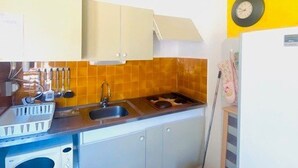 Una cocina compacta con lavamanos, estufa y armarios.