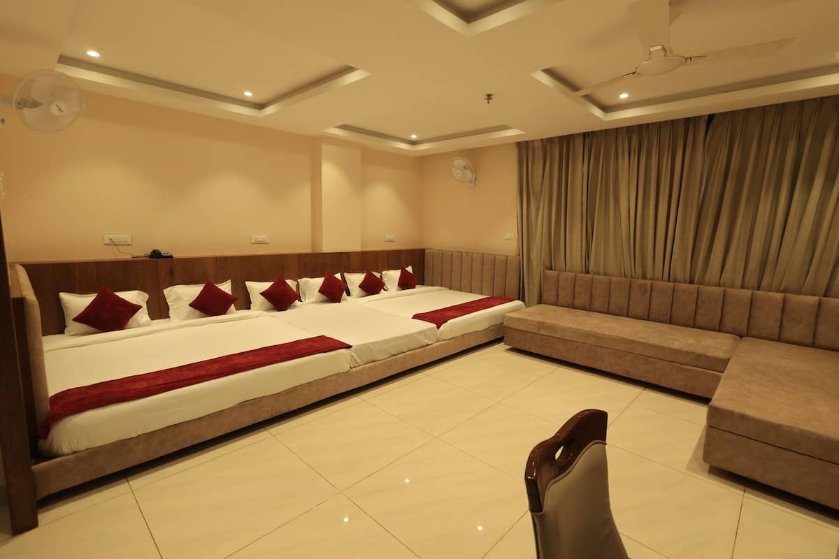 A hotel room with a large bed, a sofa, a chair, and a ceiling fan.