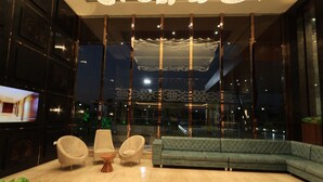 Un hall d’entrée moderne avec un canapé vert, deux fauteuils, une table basse et un téléviseur sur le côté gauche.