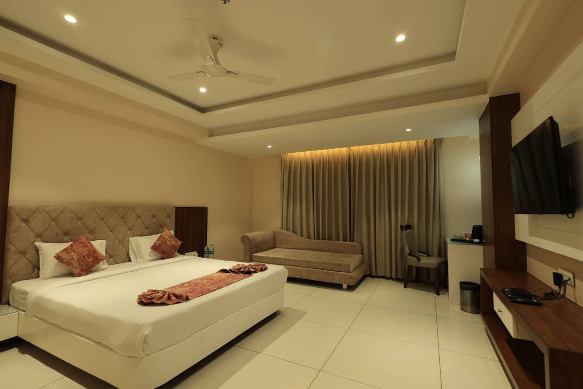 A hotel room with a large bed, a sofa, a TV, and a desk.