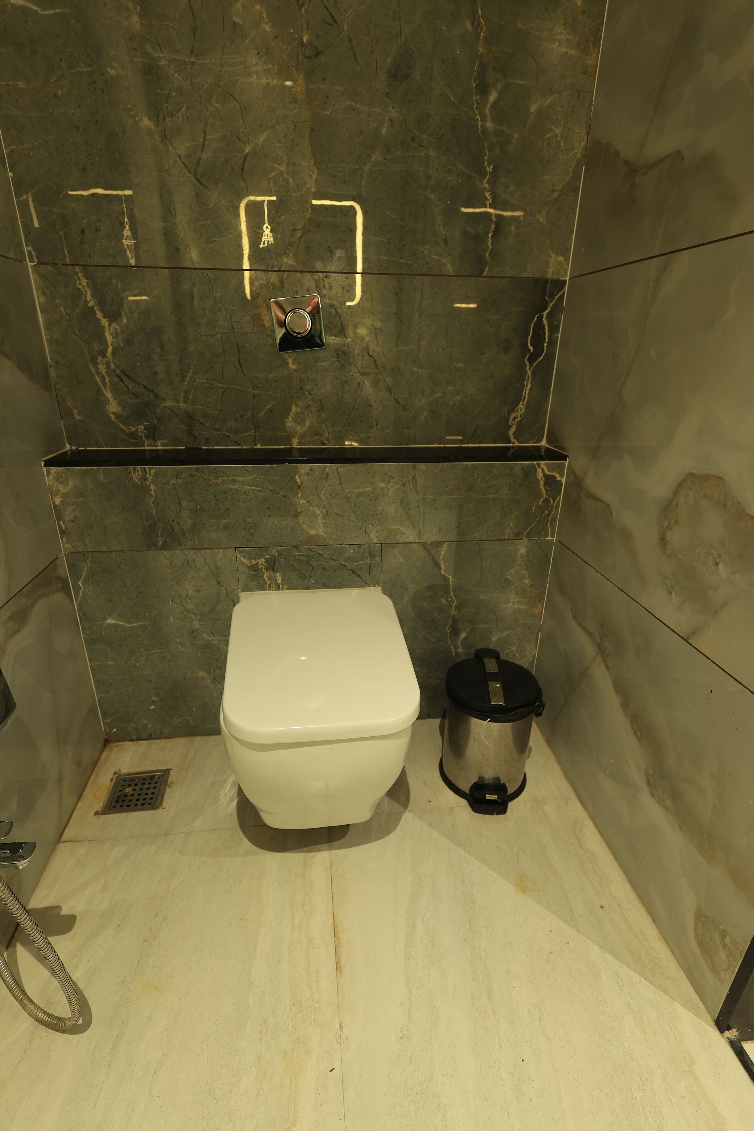 A bathroom with a toilet, a trash bin, and a shower area.