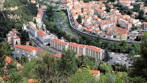 A densely packed urban area with a mix of residential and commercial buildings, featuring a curved road and a bridge. - Charming F1 with Terrace, Garage, and WiFi - Close to Spa and Town Center in Amélie-les-Bains (Amélie-les-Bains-Palalda)